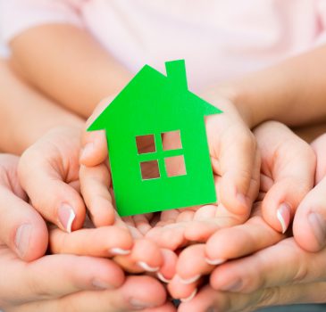 Family holding green paper house