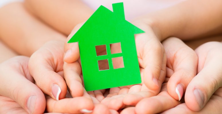 Family holding green paper house