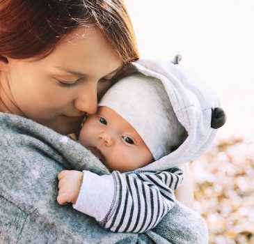 Portrait of mother and baby. Sleeping newborn baby in the hands of his mother.