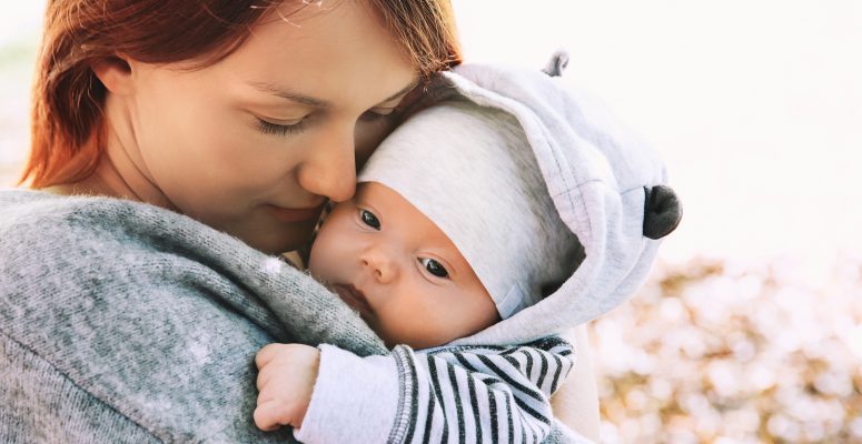 Portrait of mother and baby. Sleeping newborn baby in the hands of his mother.