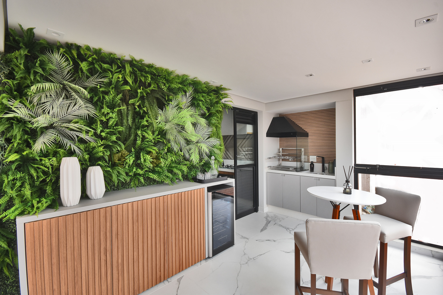 Terraço gourmet do apartamento decorado do Residencial Piemonte com churrasqueira a carvão e mesa para refeições. Todas as sugestões de decoração podem ser escolhidas por meio do pacote de personalização opcional.