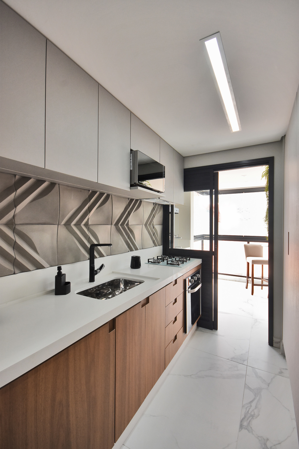 A cozinha do apartamento decorado do Residencial Piemonte com piso unificado com o da sacada dá amplitude ao ambiente. Uma das diversas possibilidades que o pacote de personalização oferece.