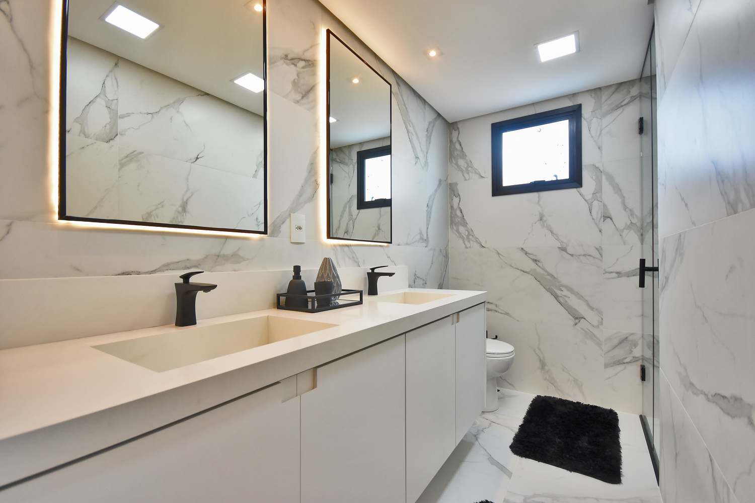 Banheiro da maior suíte do apartamento decorado do Residencial Piemonte. Os espelhos, metais pretos e revestimentos marmorizados podem ser adquiridos pelos projetos de personalização.