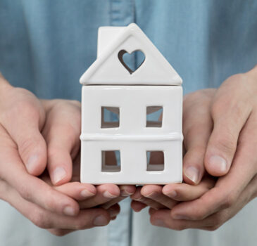 young-family-is-holding-toy-house-in-hands-cozy-man-people-home-finance-property-buy-sale-concept_t20_a8kKEx