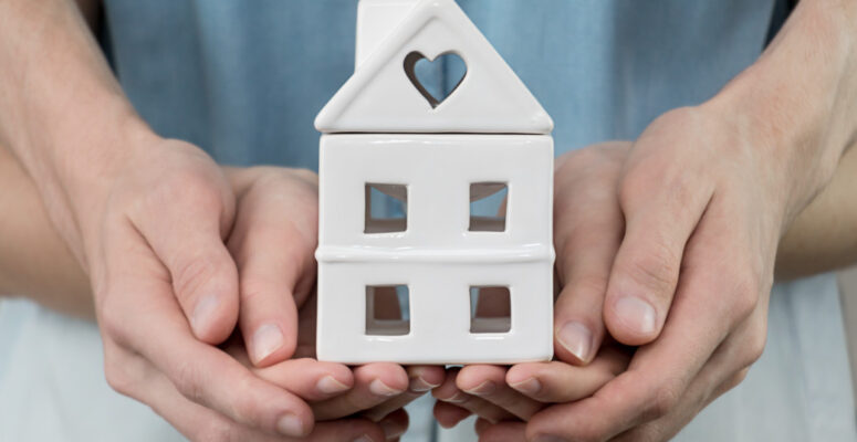 young-family-is-holding-toy-house-in-hands-cozy-man-people-home-finance-property-buy-sale-concept_t20_a8kKEx